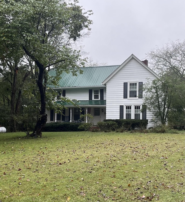 rear view of house featuring covered porch and a lawn