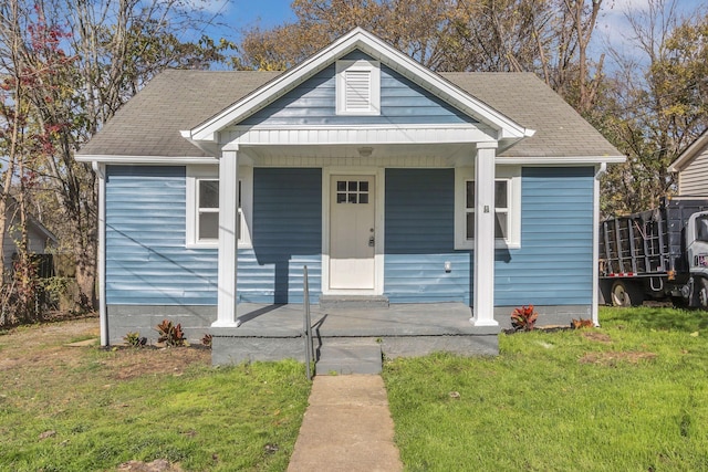 bungalow featuring covered porch and a front lawn