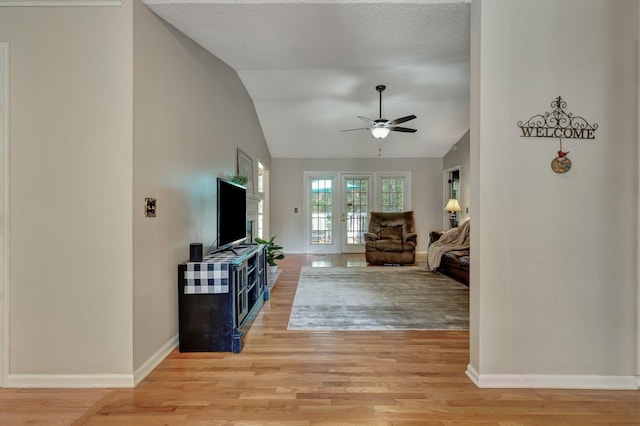 living room with ceiling fan, lofted ceiling, and light hardwood / wood-style flooring