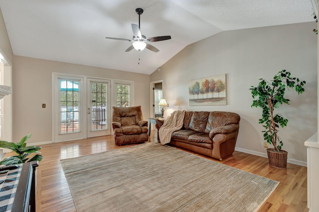 living room featuring ceiling fan, lofted ceiling, and light hardwood / wood-style floors