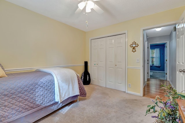 carpeted bedroom with ceiling fan, a closet, and a textured ceiling