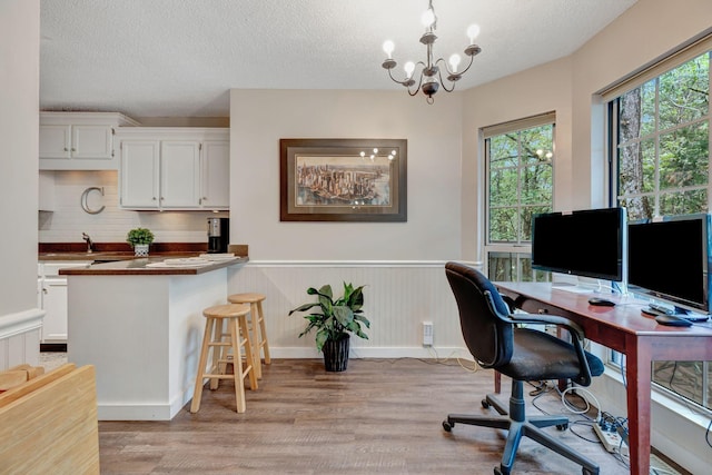 office with a notable chandelier, sink, a textured ceiling, and light hardwood / wood-style floors