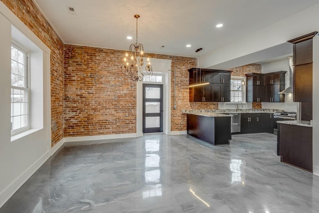 kitchen featuring dark brown cabinetry, sink, decorative light fixtures, and brick wall