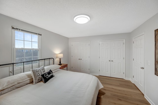 bedroom featuring hardwood / wood-style floors, a textured ceiling, and two closets