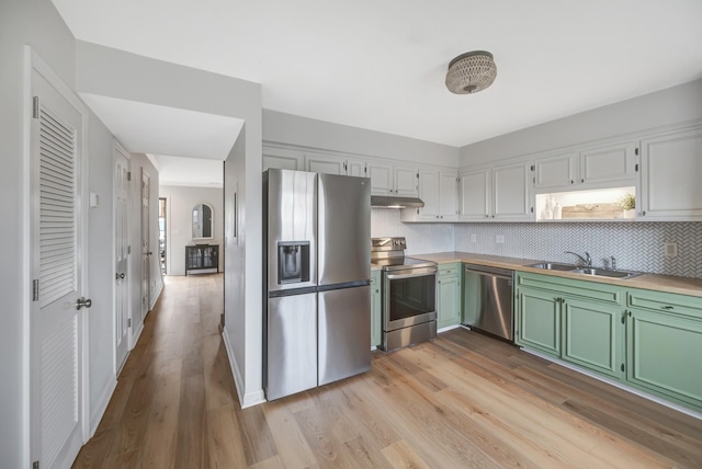 kitchen featuring white cabinetry, sink, green cabinets, light hardwood / wood-style floors, and stainless steel appliances