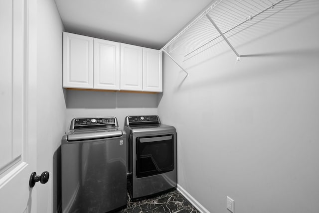 clothes washing area with cabinets and separate washer and dryer