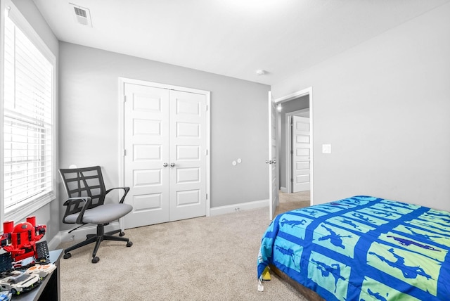 carpeted bedroom featuring multiple windows and a closet