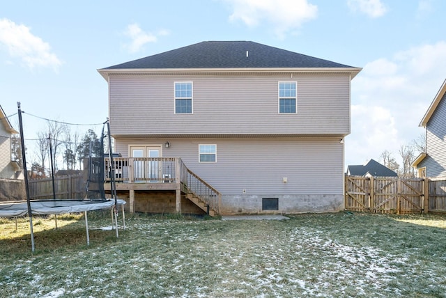 rear view of house featuring a deck, a yard, and a trampoline