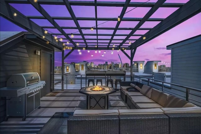 patio terrace at dusk with grilling area, a pergola, and an outdoor living space with a fire pit