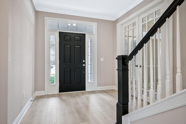 entryway with a healthy amount of sunlight, crown molding, and light hardwood / wood-style floors