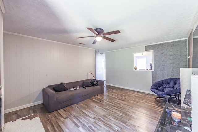 living room featuring ceiling fan, ornamental molding, and wood-type flooring