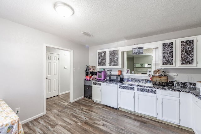 kitchen with light wood-type flooring, a textured ceiling, white dishwasher, white cabinets, and stainless steel gas stovetop