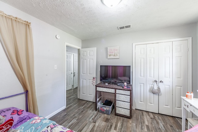 bedroom with a textured ceiling, a closet, and hardwood / wood-style floors