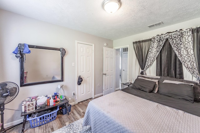 bedroom with wood-type flooring and a textured ceiling