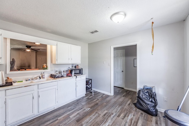 kitchen with white cabinets, hardwood / wood-style flooring, ceiling fan, and a textured ceiling