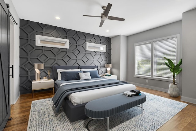 bedroom featuring ceiling fan, wood-type flooring, and a barn door