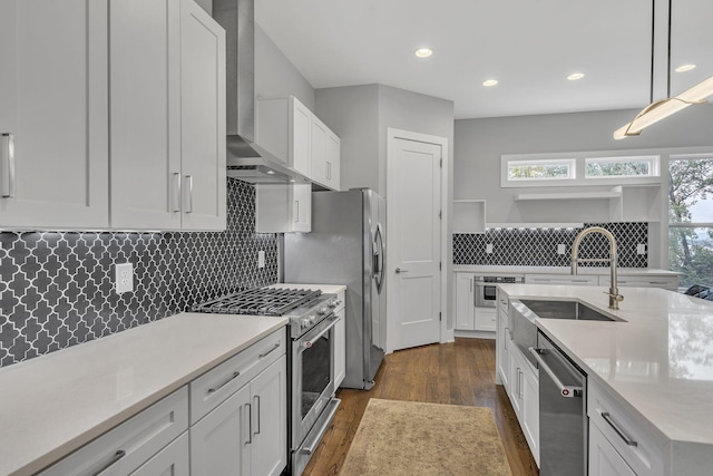 kitchen featuring white cabinetry, stainless steel appliances, wall chimney exhaust hood, and pendant lighting