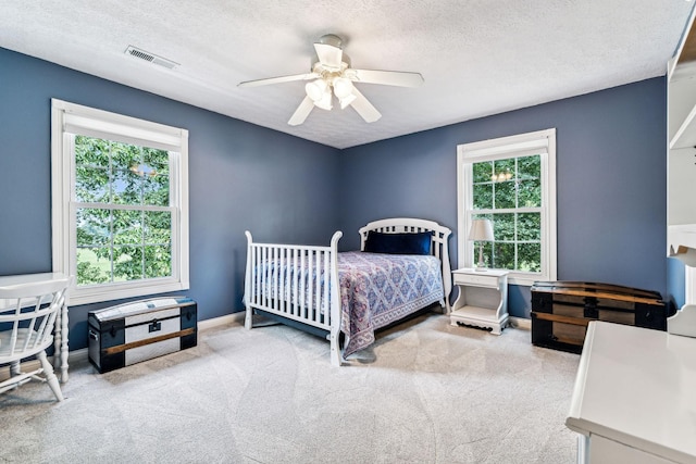 carpeted bedroom with ceiling fan and a textured ceiling