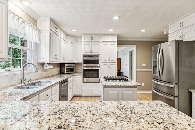 kitchen featuring white cabinetry, appliances with stainless steel finishes, sink, and light stone countertops