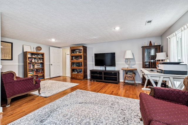 living room with a textured ceiling and light hardwood / wood-style flooring