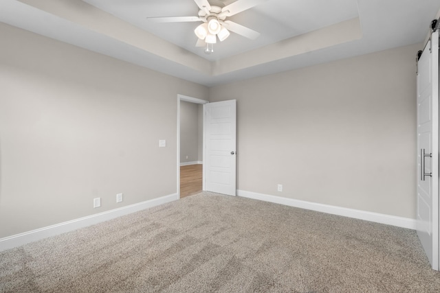 empty room featuring carpet flooring, ceiling fan, and a raised ceiling