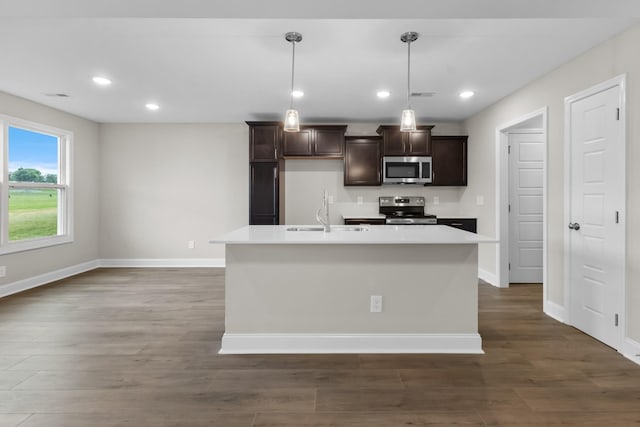 kitchen with a kitchen island with sink, hanging light fixtures, dark brown cabinetry, sink, and appliances with stainless steel finishes