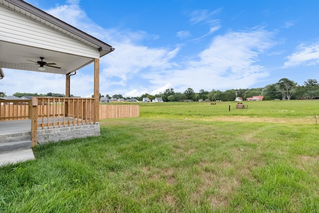 view of yard with a deck, a rural view, and ceiling fan