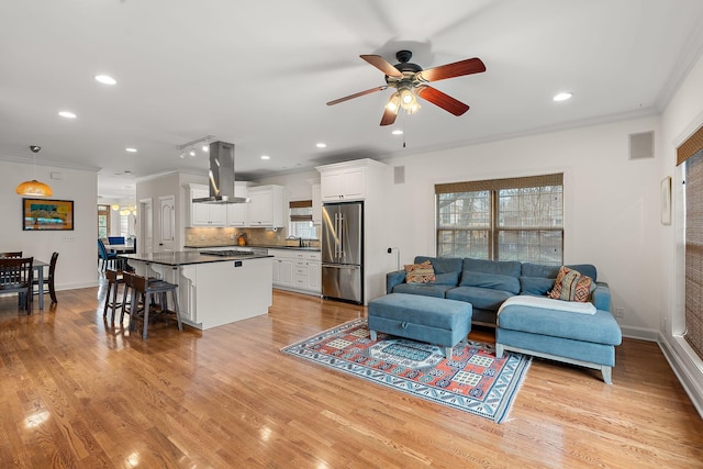 living room with ornamental molding, plenty of natural light, and light hardwood / wood-style floors