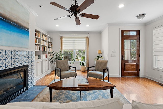 sitting room with ornamental molding, a tile fireplace, and light hardwood / wood-style flooring