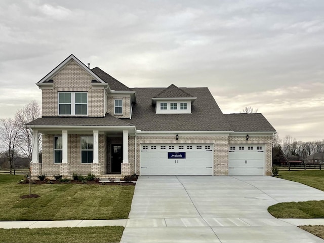 craftsman house with an attached garage, brick siding, driveway, and a front yard