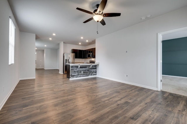 unfurnished living room with ceiling fan, recessed lighting, dark wood finished floors, and baseboards