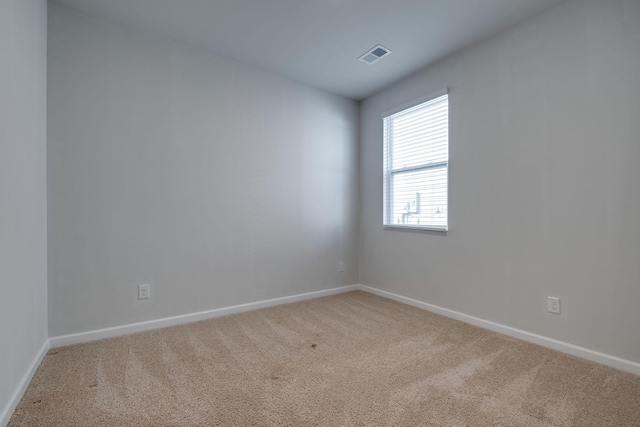 spare room featuring light carpet, baseboards, and visible vents