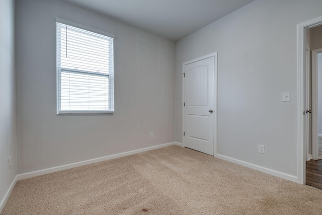 unfurnished room featuring light colored carpet and baseboards