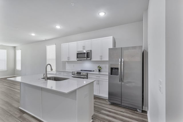 kitchen featuring appliances with stainless steel finishes, sink, white cabinetry, and a kitchen island with sink