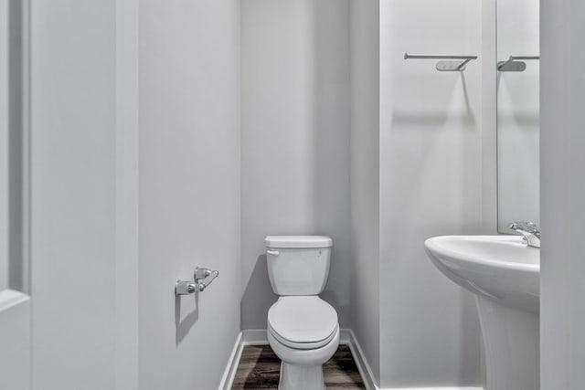 bathroom with toilet, sink, and wood-type flooring