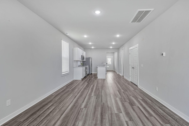 unfurnished living room featuring sink and light hardwood / wood-style floors