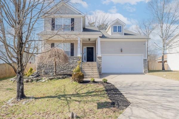 view of front of property with an attached garage, fence, concrete driveway, stone siding, and a front yard