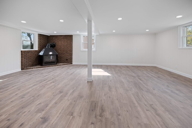 basement with a wood stove and light hardwood / wood-style floors