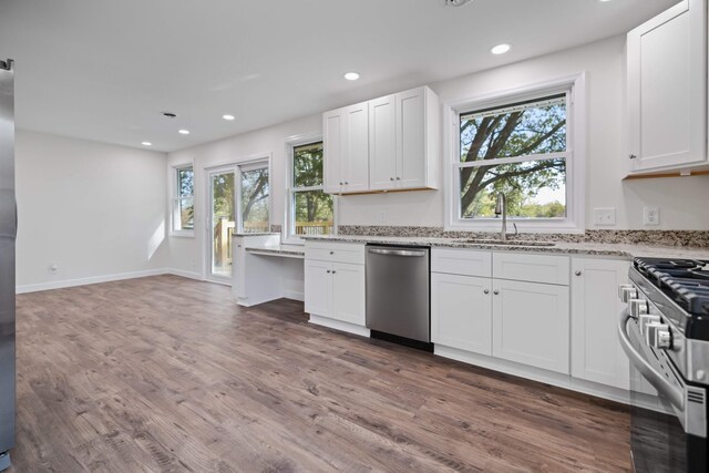 kitchen featuring stainless steel appliances, dark hardwood / wood-style flooring, light stone countertops, sink, and white cabinets