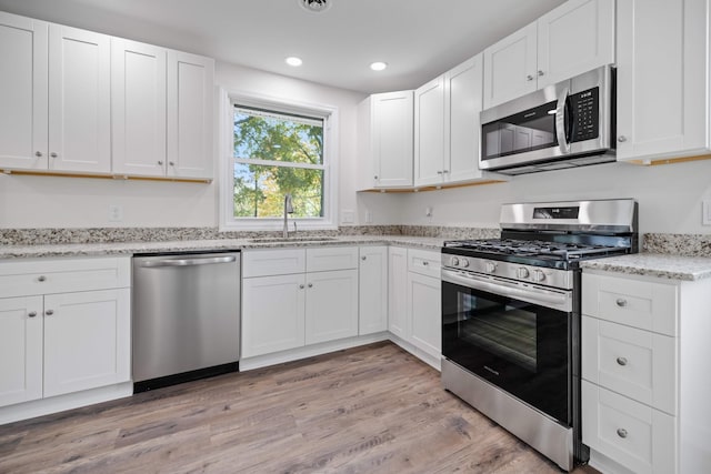 kitchen with sink, light wood-type flooring, white cabinetry, and stainless steel appliances