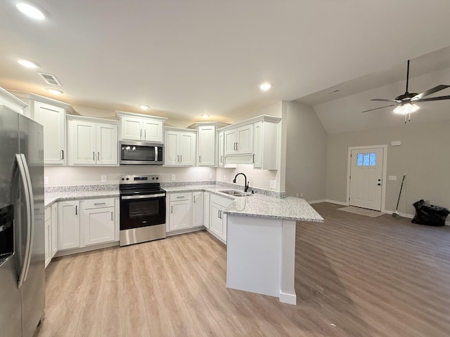 kitchen featuring appliances with stainless steel finishes, light wood-type flooring, white cabinets, sink, and kitchen peninsula