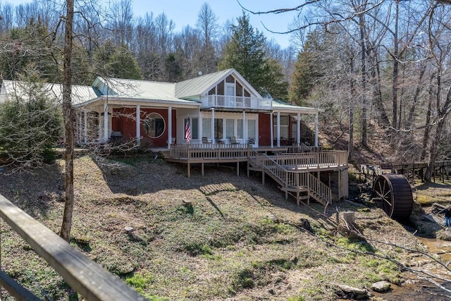 rear view of property featuring metal roof, stairway, and fence