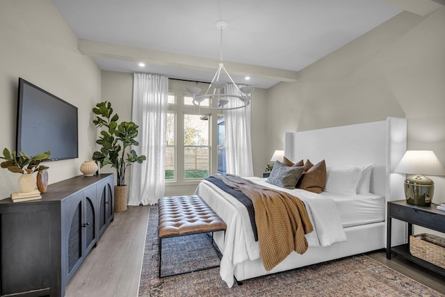 bedroom featuring beam ceiling, an inviting chandelier, and wood-type flooring