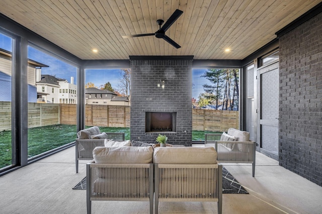 sunroom / solarium featuring ceiling fan, an outdoor brick fireplace, a healthy amount of sunlight, and wood ceiling