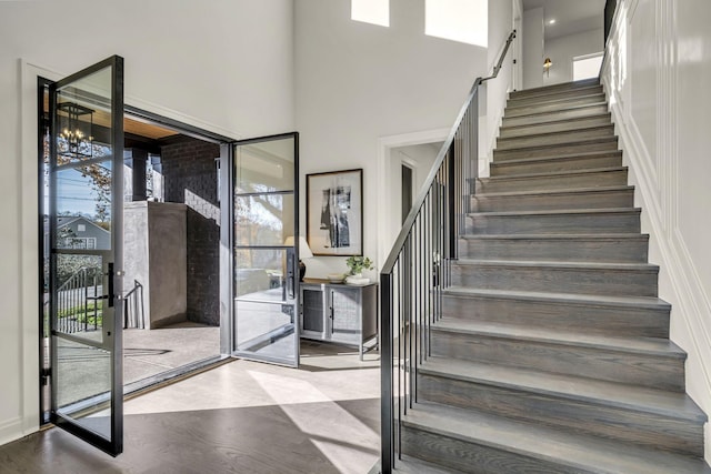 stairs featuring hardwood / wood-style floors, a wealth of natural light, and a high ceiling