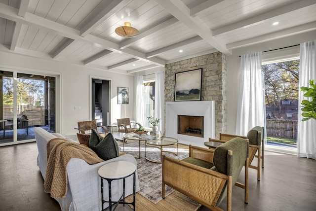 living room with hardwood / wood-style floors, beamed ceiling, and a stone fireplace