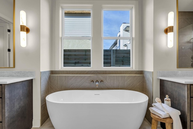 bathroom with tile walls, a tub, and vanity