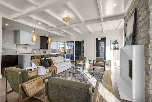 living room featuring wood-type flooring, a large fireplace, and beam ceiling