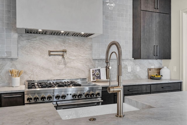 kitchen featuring dark brown cabinetry, high end stainless steel range oven, light stone countertops, tasteful backsplash, and custom range hood