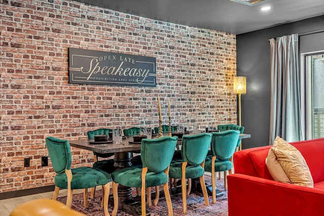 dining room with hardwood / wood-style flooring and brick wall